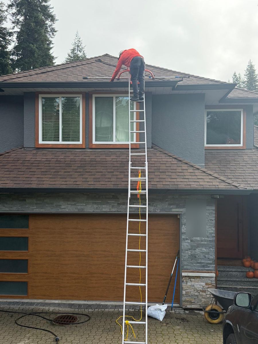 Technician cleaning gutters on a two-storey North Shore home